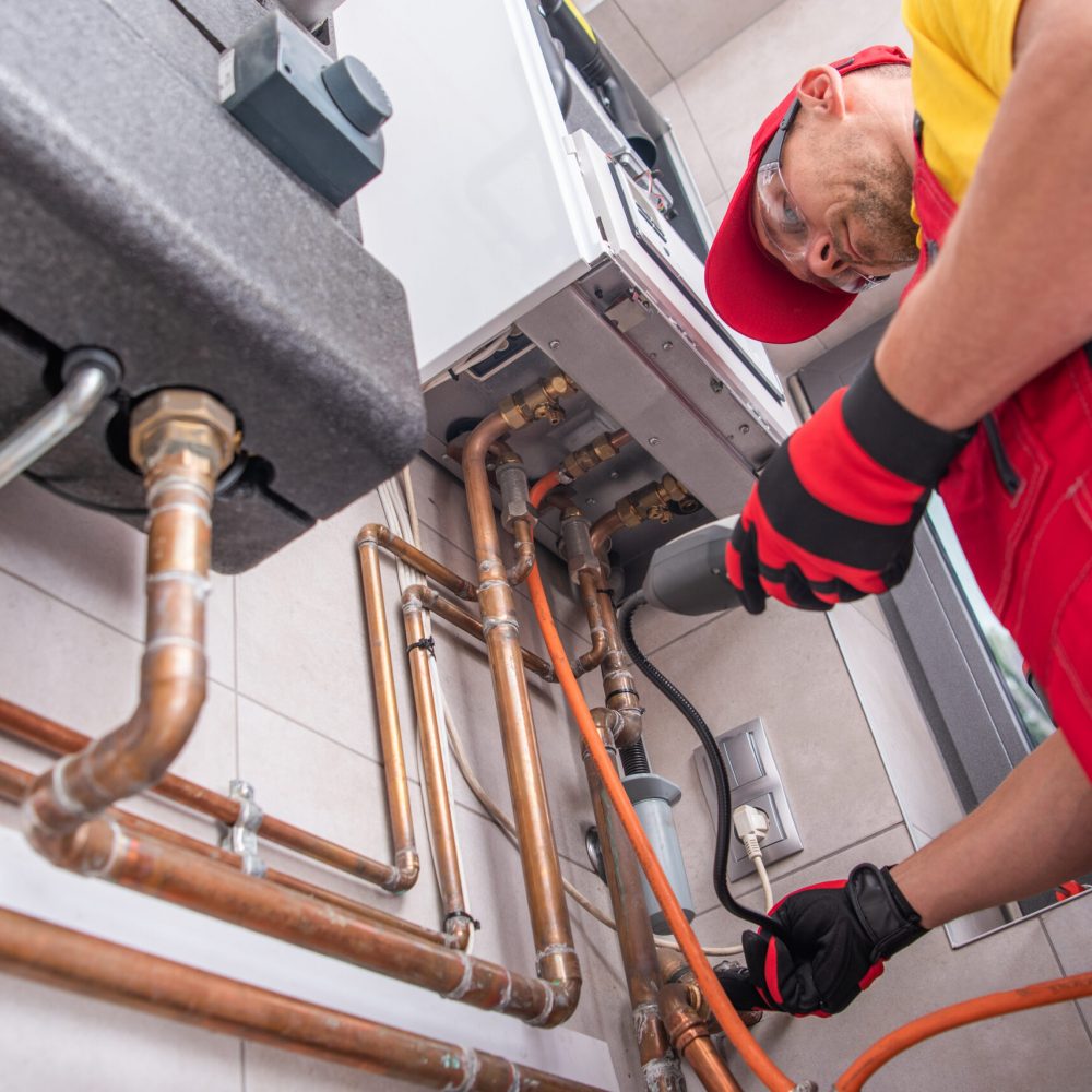 Professional Gas Heating Technician with Natural Gas Detector Device in His Hands Looking For Potential Leaks Inside the Heating Furnace System.